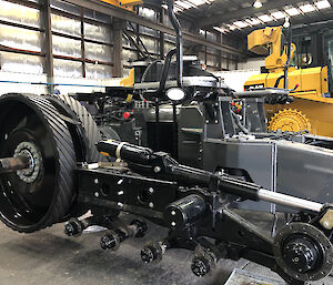 Black and grey metal machinery of a stripped-down tractor in a workshop