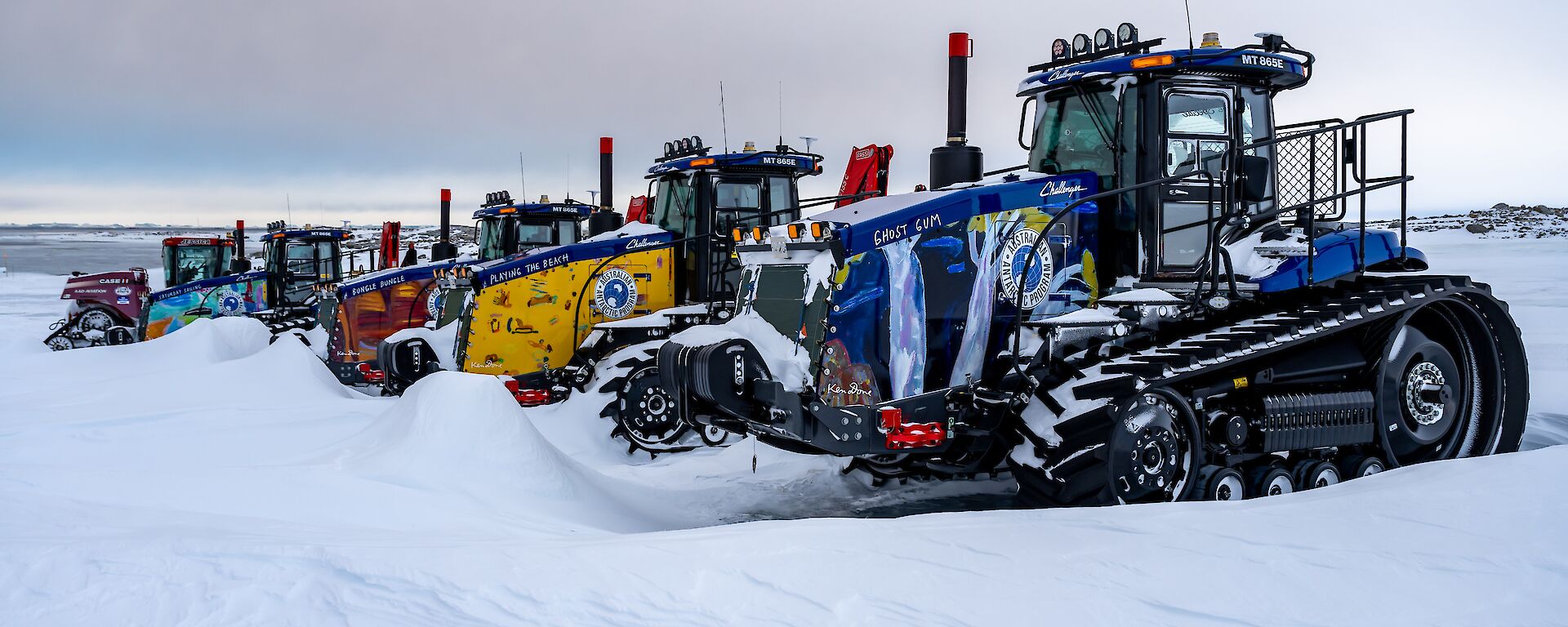 A row of tractors parked in the snow.