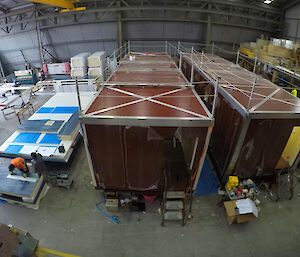A wide-angle view of a construction warehouse, showing accommodation vans being worked on