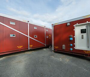 Exterior of red portable living quarters, sitting on concrete.