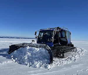 A vehicle pushes snow in an icy landscape.