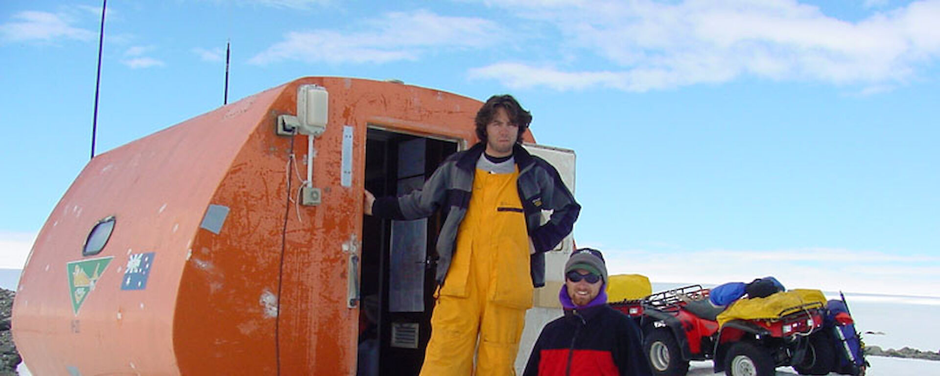 Two people standing next to a round hut in Antarctica