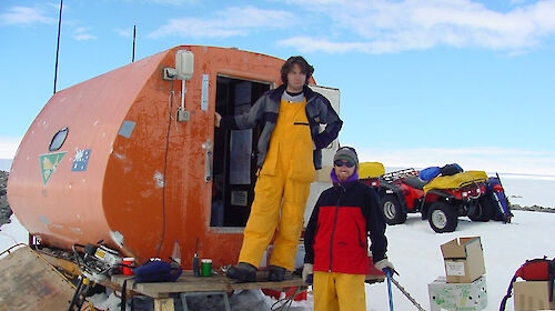 Two people standing next to a round hut in Antarctica