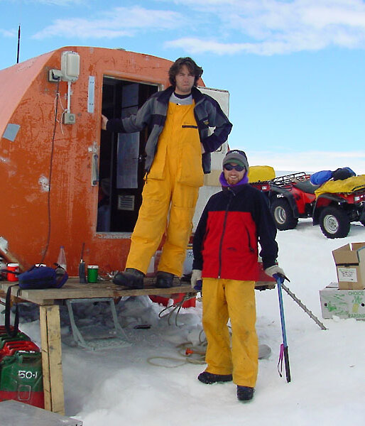 Two people standing next to a round hut in Antarctica
