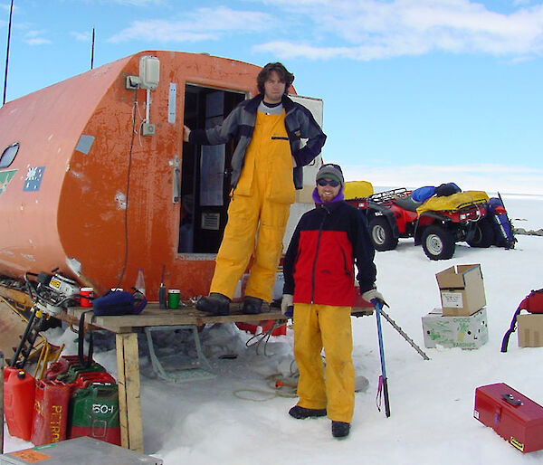 Two people standing next to a round hut in Antarctica