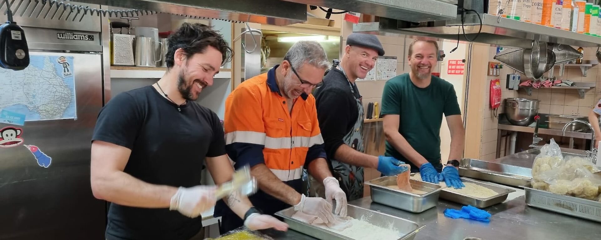 Four people smiling whilst crumbing chicken fillets at Casey kitchen