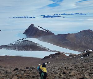 An expeditioner in the foreground with a rising mountains in the distance