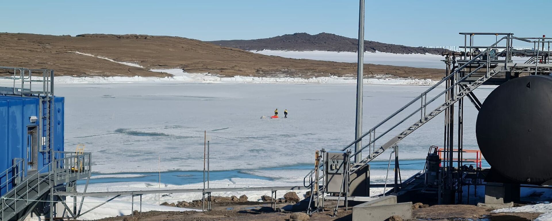 Two people walking across sea ice in the distance