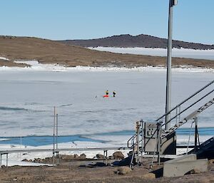 Two people walking across sea ice in the distance