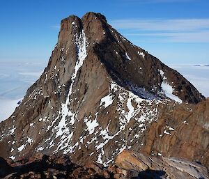 A jagged mountain peak covered in ice with clear skies behind