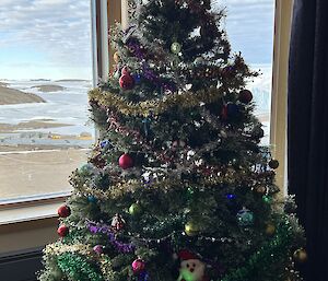 A christmas tree with a view of Antarctica outside the window