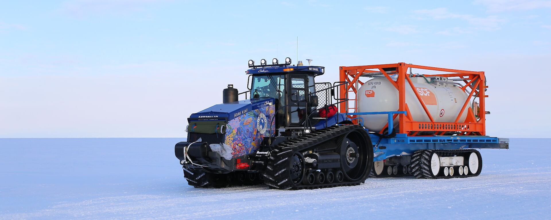 A colourful tractor in a snow covered landscape.