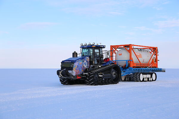 A colourful tractor in a snow covered landscape.