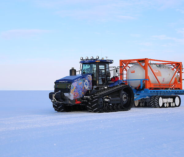 A colourful tractor in a snow covered landscape.