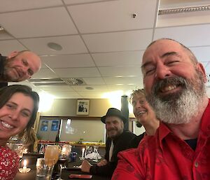 A selfie shot of five smiling people looking down towards the camera