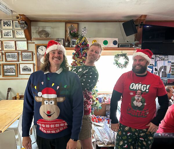 Three men in Christmas outfits smiling