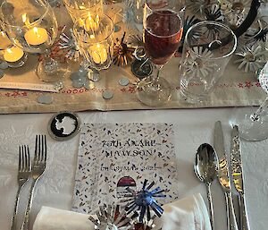 Table setting with cutlery, glasses, candles, napkin and Christmas menu