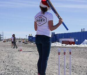 Person shaping up to bat with a cricket bat in front of stumps on a gravel wicket