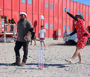 Person in a christmas outfit bowling a tennins ball on gravel cricket pitch
