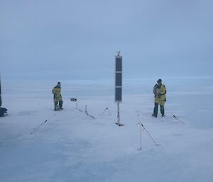 Two Antarctic expeditioners anchoring science instruments in the ice