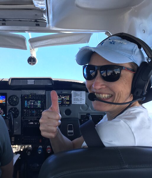 A woman smiles from the cockpit of a small plane