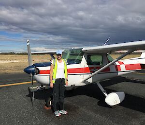 A woman stands next to a plane