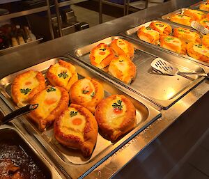 Four silver bain-marie trays filled with egg, cheese and parsley pastries