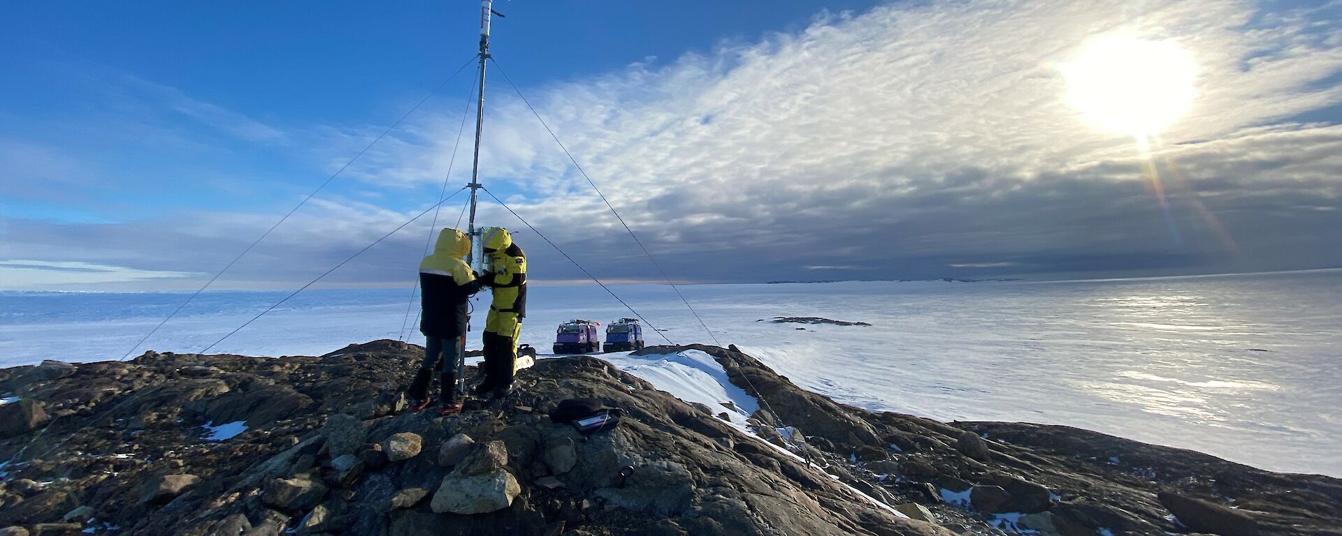 Two expeditioners on top of a barren hill in Antarctica