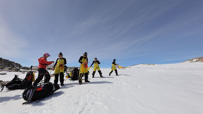 A field training officer shows four people how to do sea ice rescue using ropes