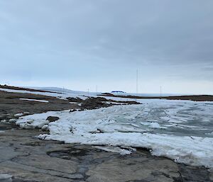 View of Horseshoe Harbour with rocky shoreline and sea ice which is starting to melt and break up