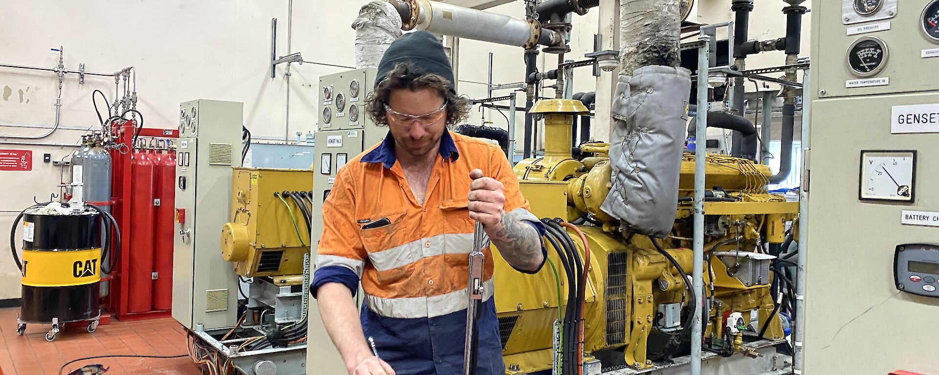 Man stands at workbench in powerhouse, adjusting bolts on generator filter