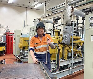 Man stands at workbench in powerhouse, adjusting bolts on generator filter