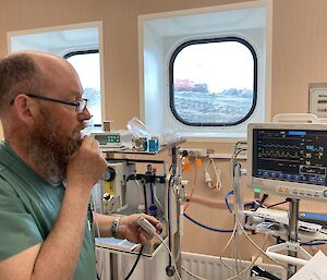 Man looks at blood pressure monitor in medical facility