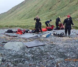 A group in wet weather gear unpack supplies on a grey beach
