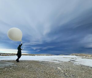 Meteorology observer walking with weather balloon with dramatic clouds above