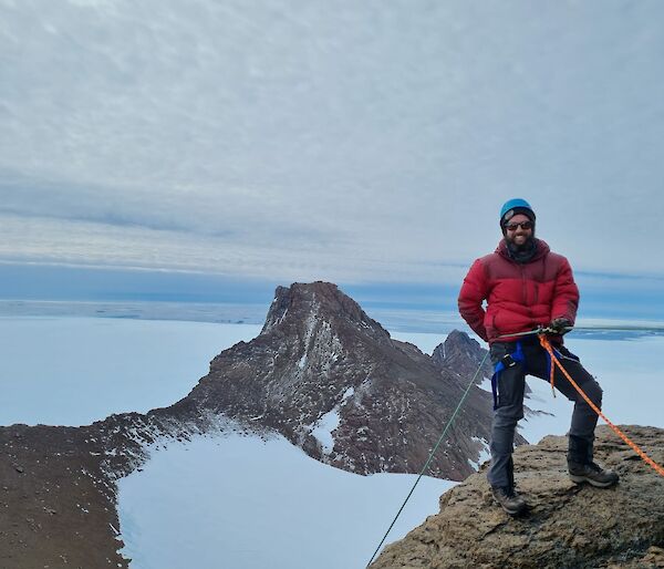 Man roped up for abseiling stands at edge of drop ready to descend