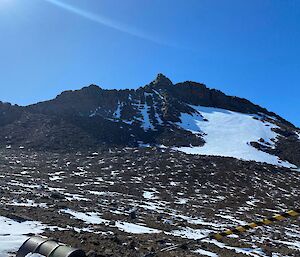 Looking up a rocky slope and mountain peak, with blue skies above