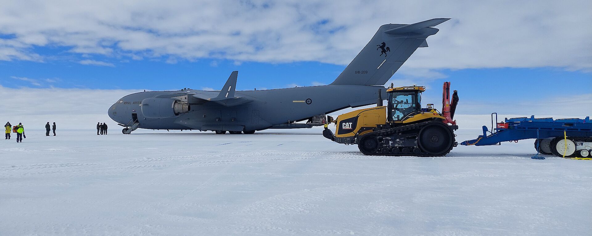 A Boeing C-17 Globemaster parked on ice with a refuelling tractor in the foreground