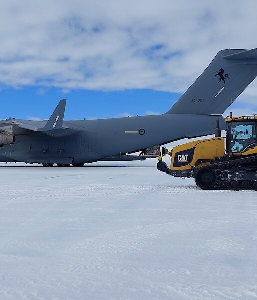 A Boeing C-17 Globemaster parked on ice with a refuelling tractor in the foreground