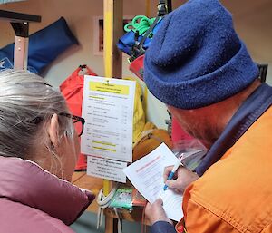 Two people with a checklist are undertaking training in a warehouse