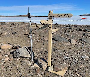 A wooden sign showing various directional waypoints to Casey station, the airfield, windsock and more.