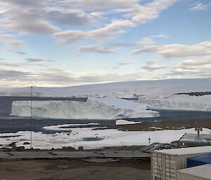 An iceberg has broken away from the shore and floats in the bay