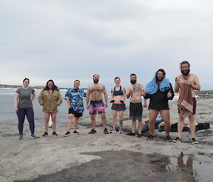 A group of swimmers are ready to take the plunge on a very cold grey day