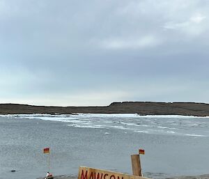 A sign saying "Mawson Sea Baths" stands in front of a cold and icy bay