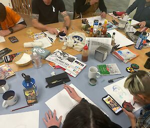 Group of people seated at a table painting and drawing