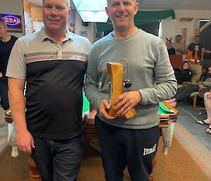 Two pool players posing for a photo in front of a pool table.