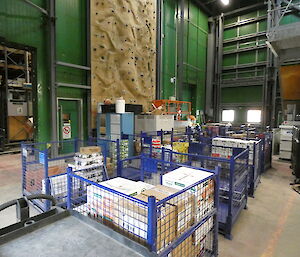 numerous blue wire-cages containing boxes of food inside a very large green warehouse