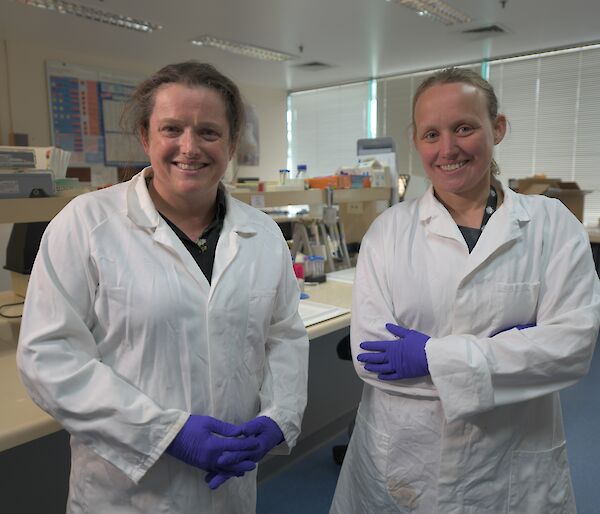 Two women in lab coats standing side by side