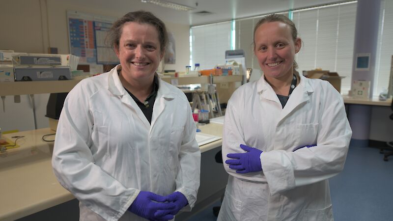Two women in lab coats standing side by side