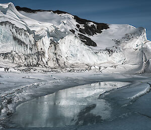 An ice cliff sits dramatically under a grey sky